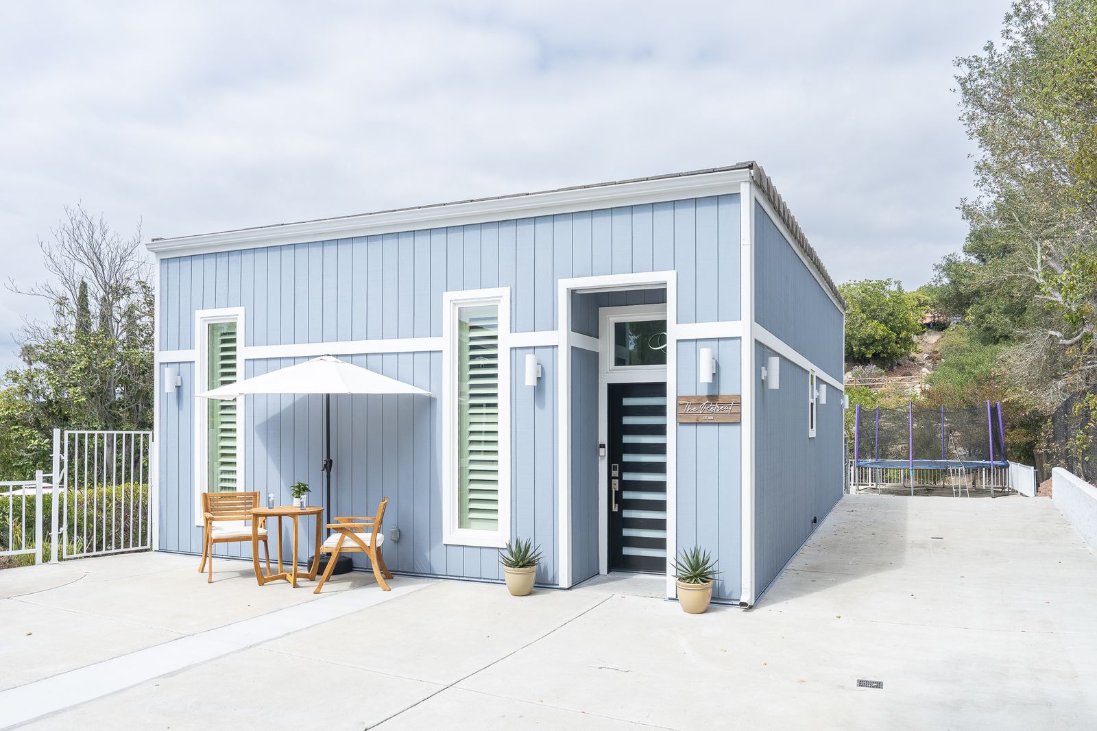 Rancho Bernardo detached ADU: a blue board-and-batten casita with a covered entry and a patio set beside the driveway