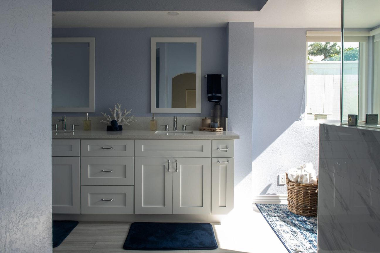 Oceanside accessible bathroom remodel with a curbless shower, a white double vanity and a wide doorway