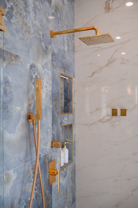 Luxury shower system with brass rain head, handheld wand, and valve trim on blue tile