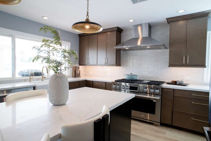 Kitchen island in the foreground with the range and stainless hood along the back wall