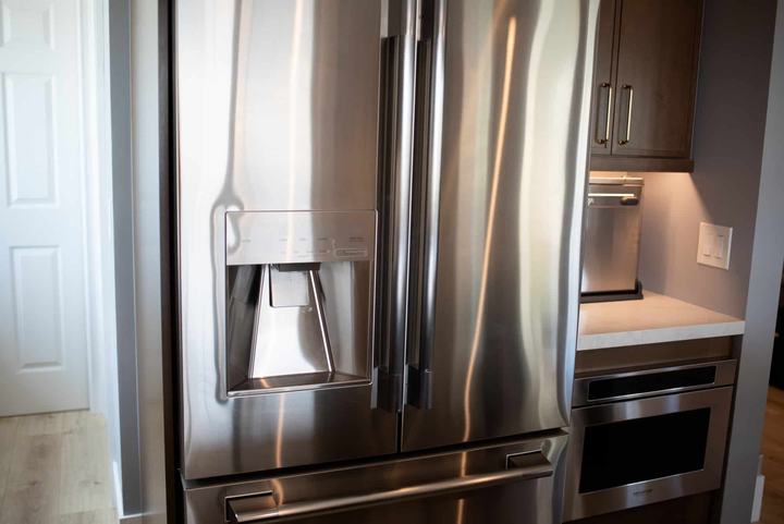 Stainless french door refrigerator beside the built-in microwave drawer and appliance niche