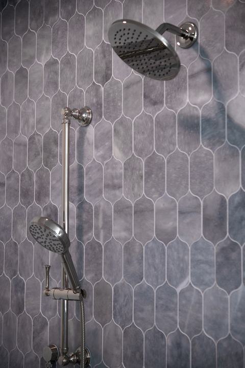 Chrome rain shower head and handheld sprayer on blue-gray lotus tile shower wall