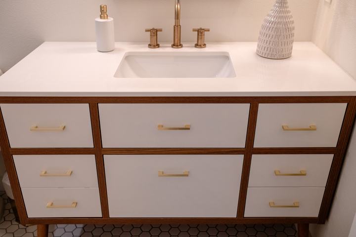 Hall bathroom vanity with white fronts and brass pulls