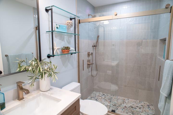 Hall bathroom with a wood vanity, glass wall shelves, and a walk-in shower behind sliding glass