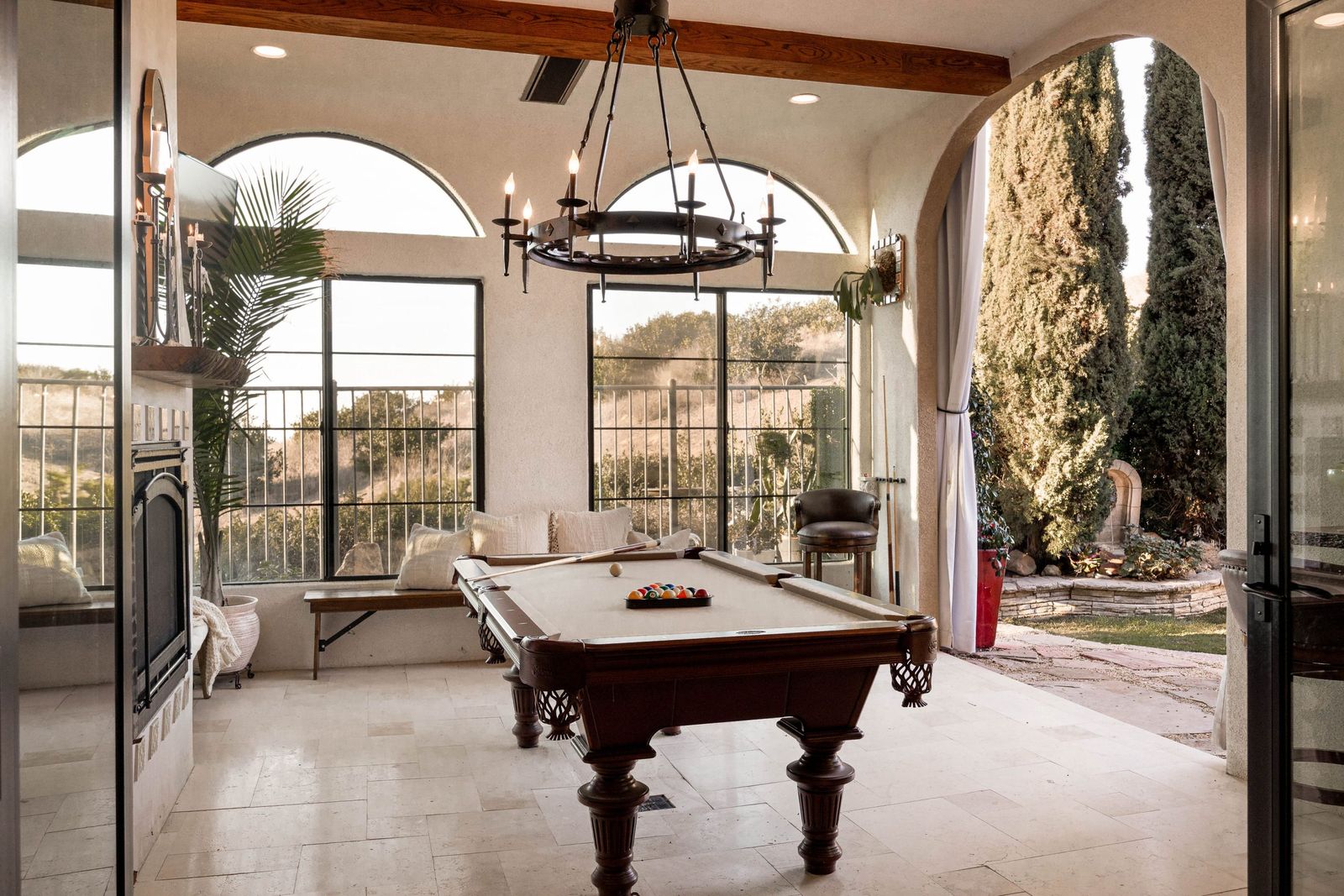 Chula Vista California room with a pool table under an iron chandelier, arched windows and steel doors to the garden