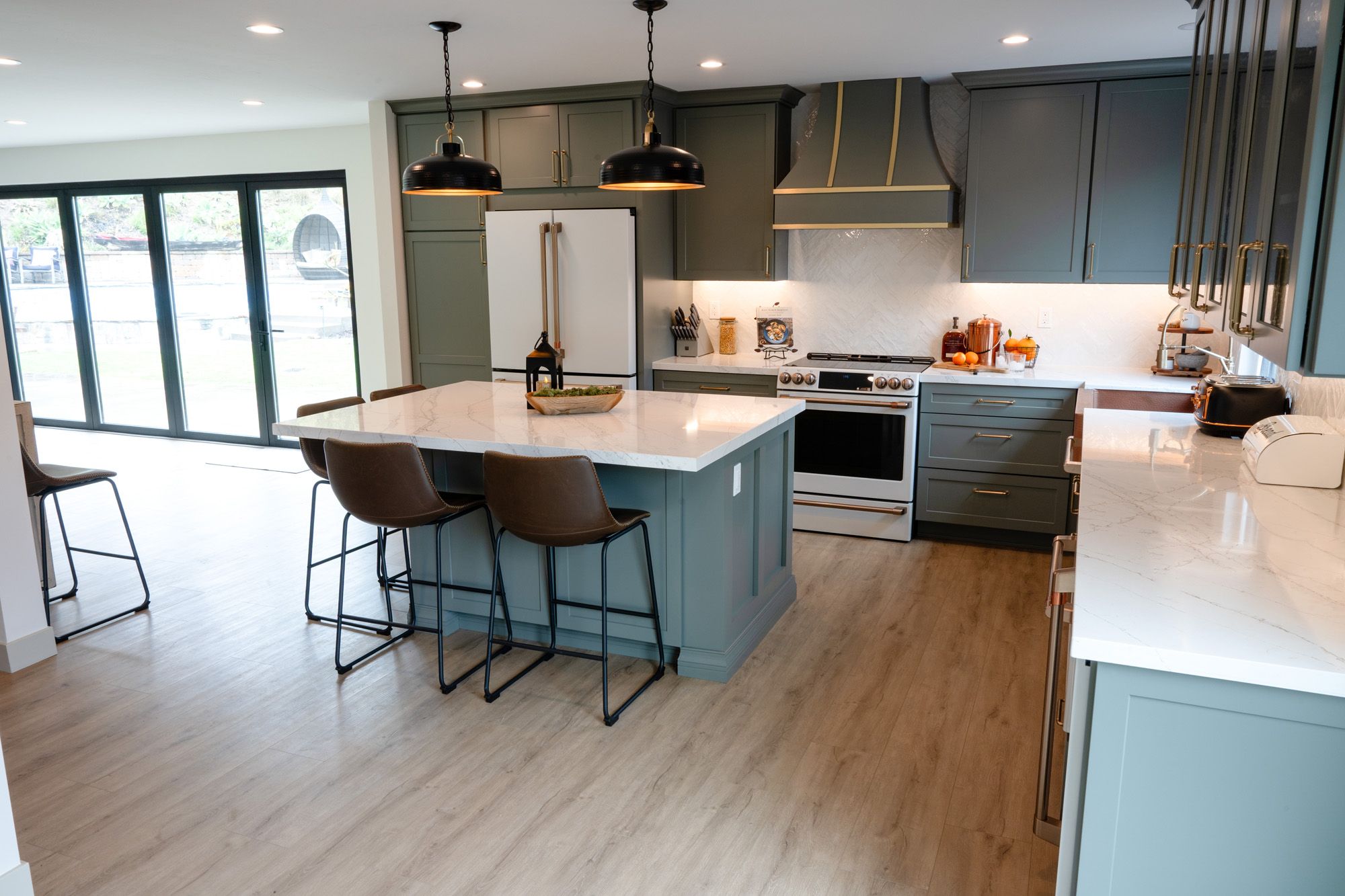 Whole home remodel in San Diego: a 1960s floor plan opened into one great room with a sage-green kitchen, an island and wall-to-wall glass