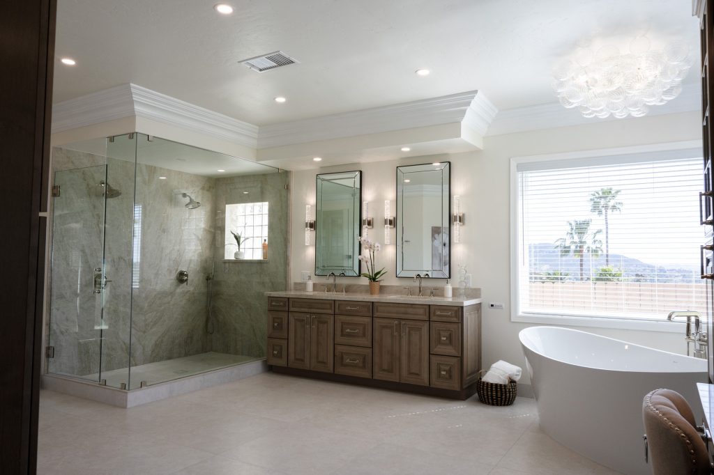 Wide room view showing quartzite slab shower, double vanity, freestanding tub and chandelier
