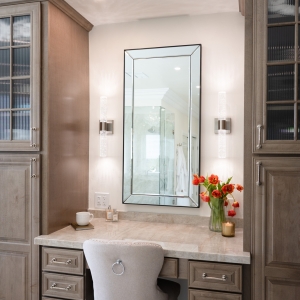 Front view of built-in makeup station, mirror flanked by sconces and tulip arrangement