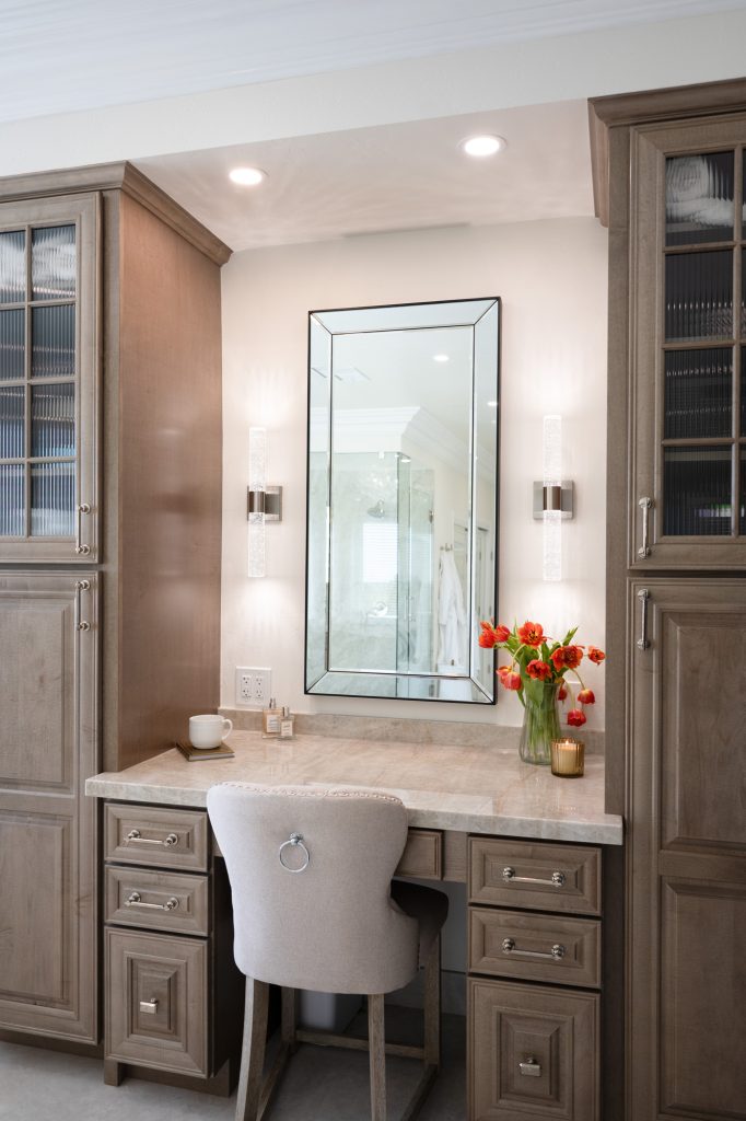 Front view of built-in makeup station, mirror flanked by sconces and tulip arrangement