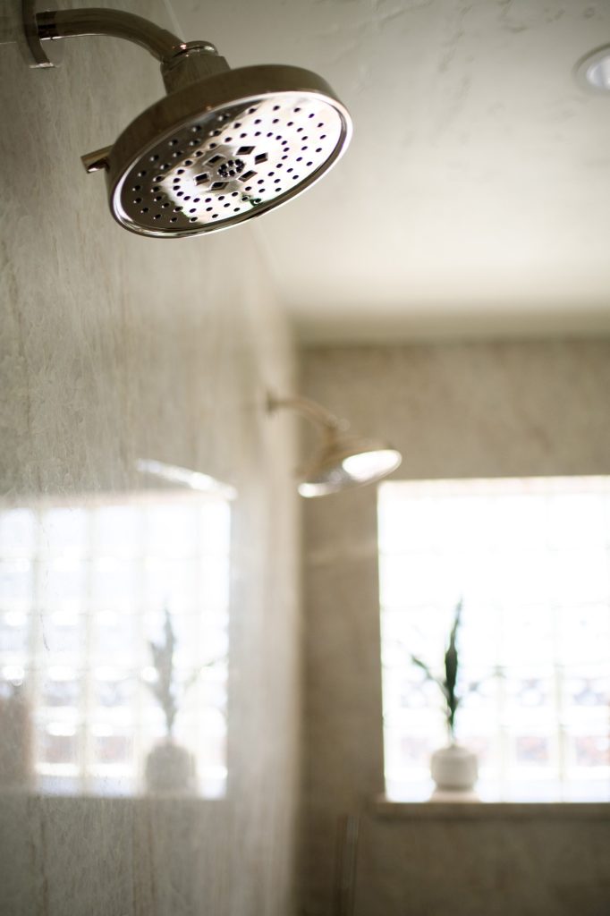 Close-up of Brizo Invari multi-function showerhead against quartzite wall, soft focus background