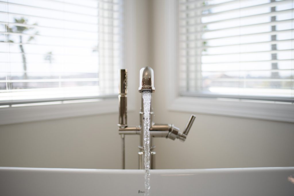 Close-up of polished-nickel Brizo tub filler splashing water in the BainUltra Evanescence tub