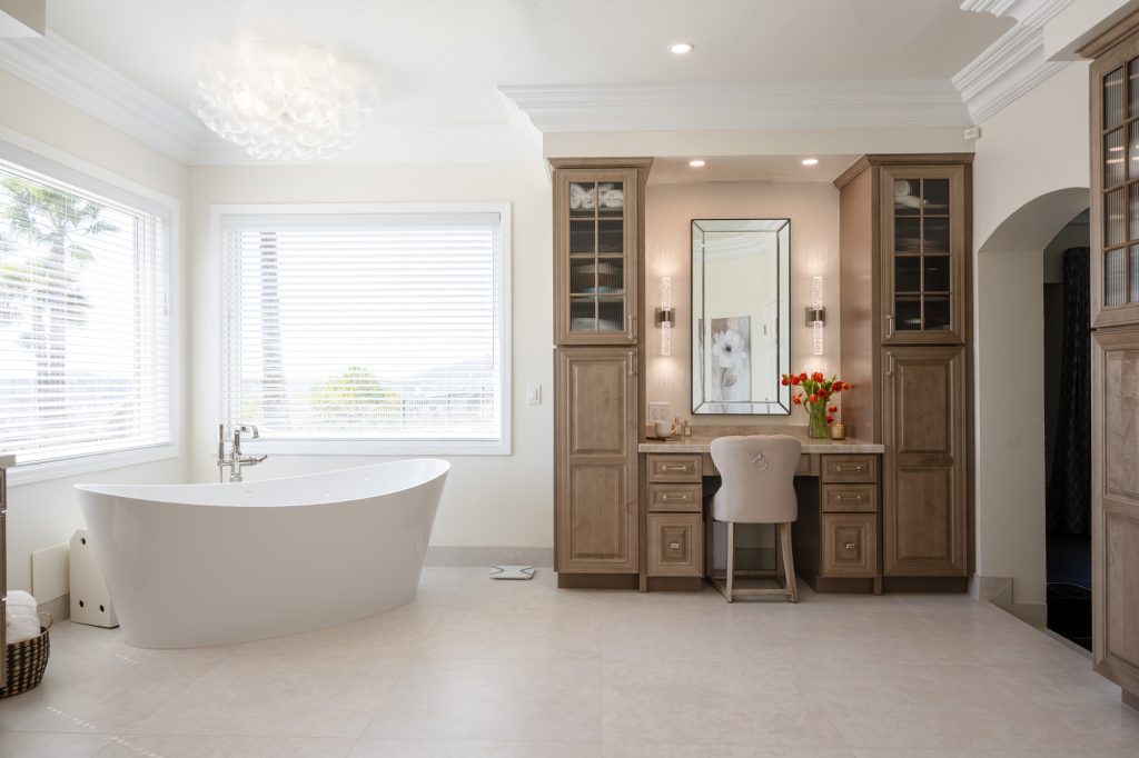 Freestanding micro-bubble tub under bubble-glass chandelier next to makeup vanity and linen towers