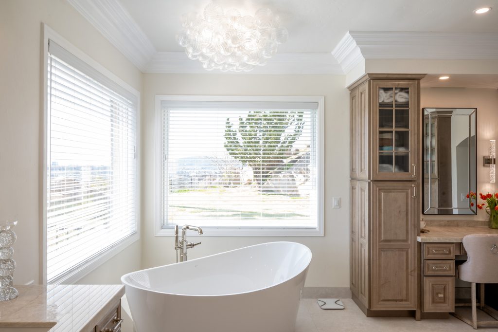 Freestanding tub beneath bubble chandelier with panoramic Poway view through large window