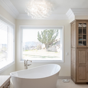 Freestanding tub beneath bubble chandelier with panoramic Poway view through large window