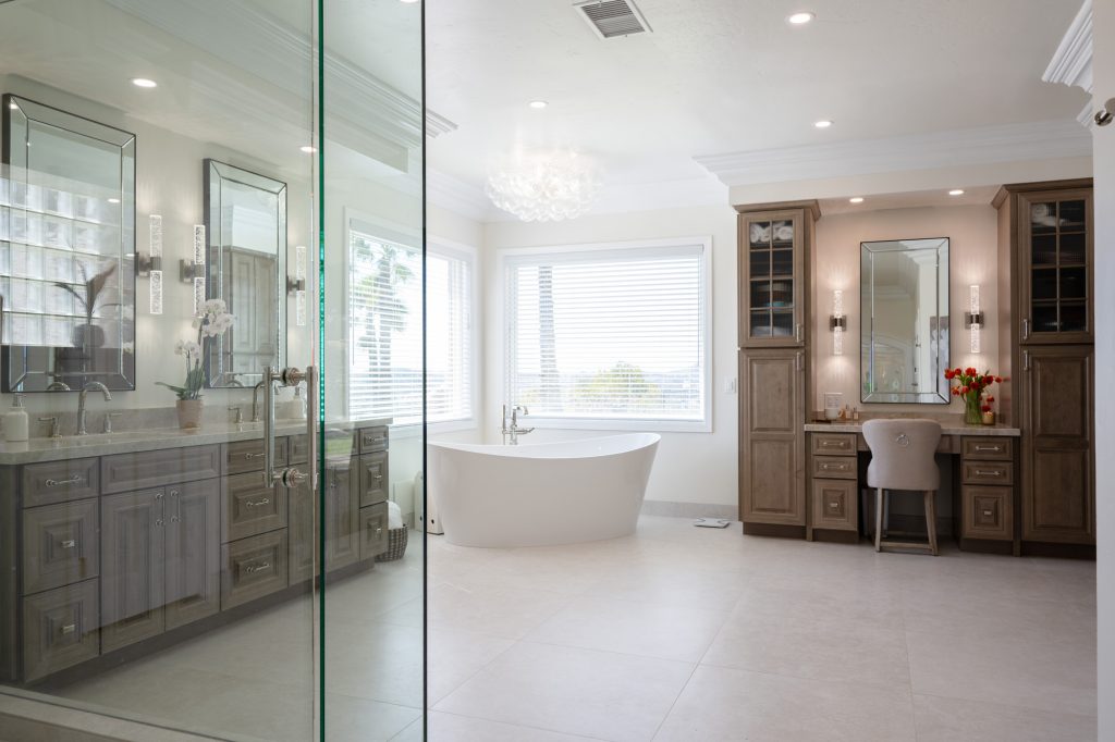 Wide shot of tub, vanity and slab-wall shower reflected in frameless glass enclosure