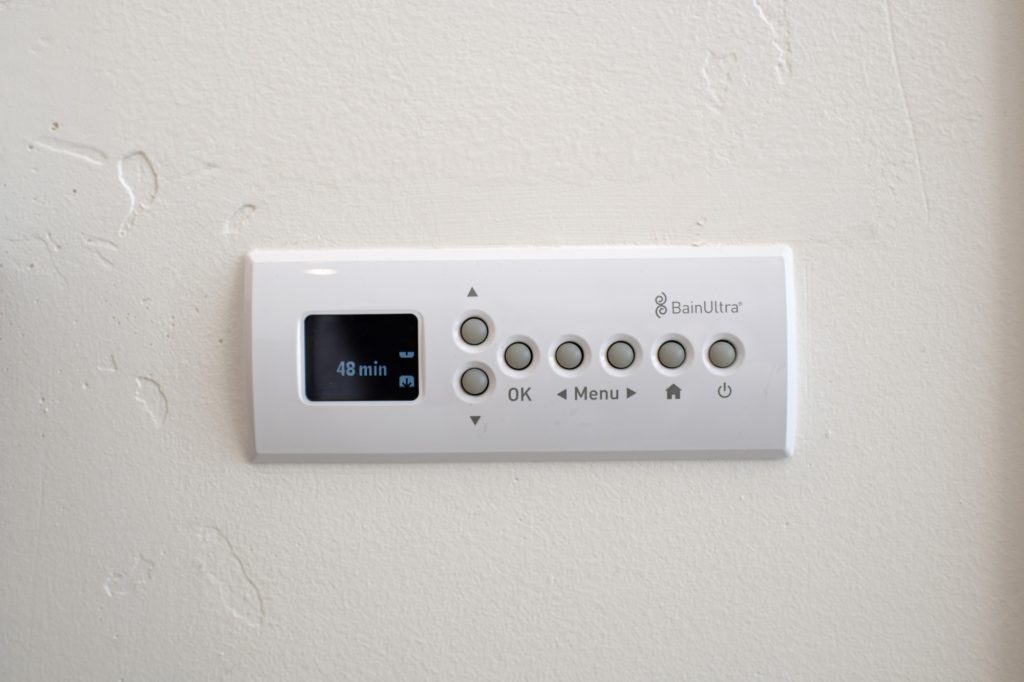 BainUltra digital control panel for the heated micro-bubble bathtub mounted on the bathroom wall.