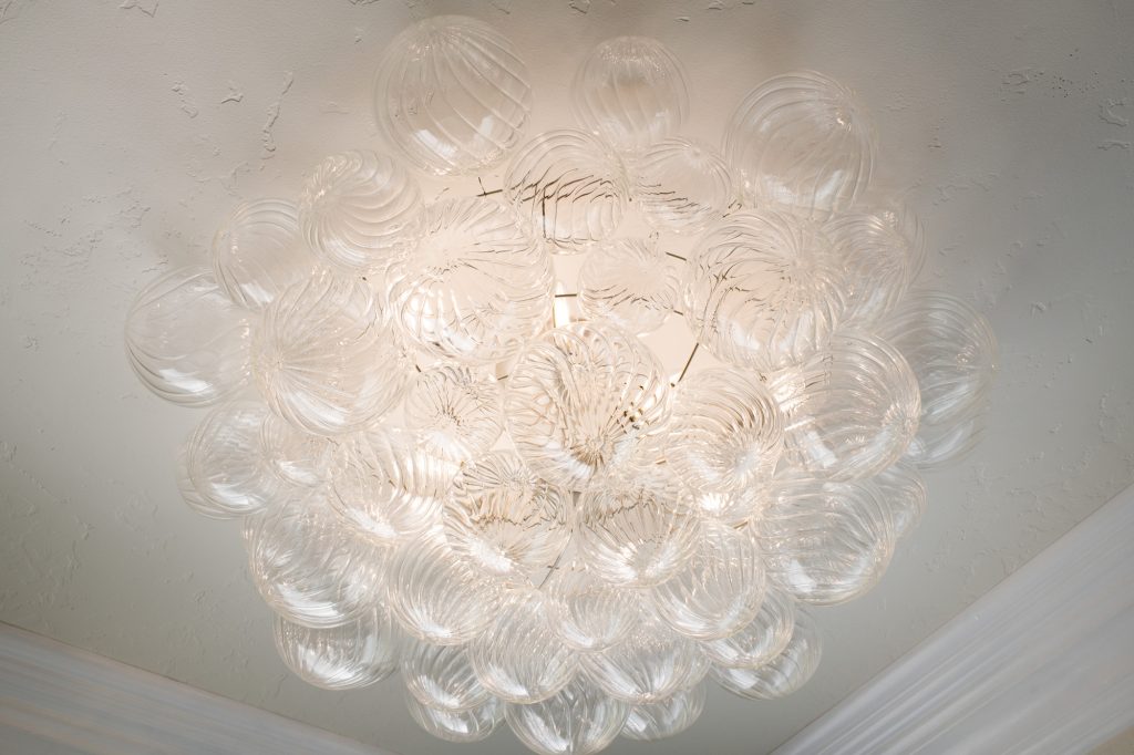 Bubble chandelier centered on cove ceiling in the luxurious primary bath.