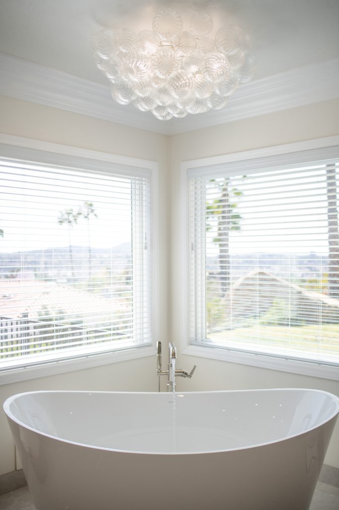 Sculptural bubble-glass chandelier sparkling above the soaking tub with panoramic hillside views.