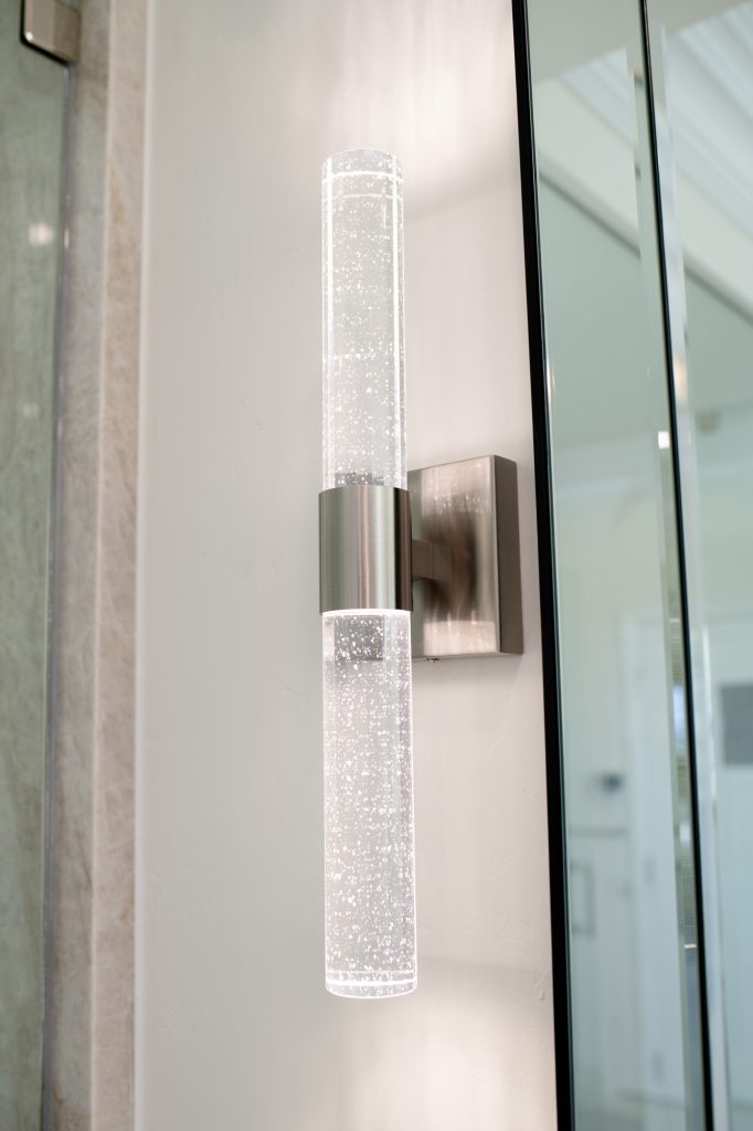 Sparkling crystal-rod wall sconce providing ambient lighting by the vanity mirror.