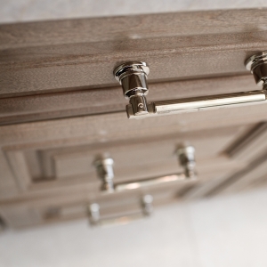 Angled detail of polished-nickel appliance pull on custom maple drawer front in the luxury vanity.