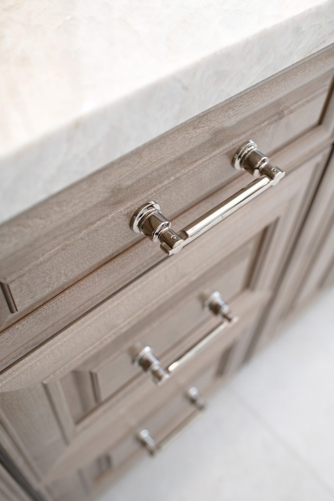 Vertical view highlighting polished-nickel drawer pull and thick Perla Venata quartzite countertop edge.