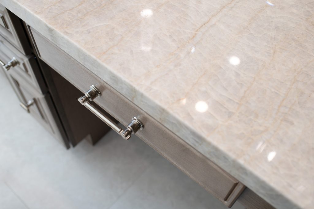 Close-up of shimmering Perla Venata quartzite countertop with polished-nickel pull beneath.
