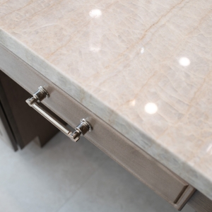 Close-up of shimmering Perla Venata quartzite countertop with polished-nickel pull beneath.
