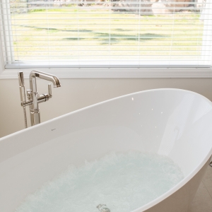 Hydrotherapy bubbles churning in BainUltra tub while hillside scenery is visible through the window.