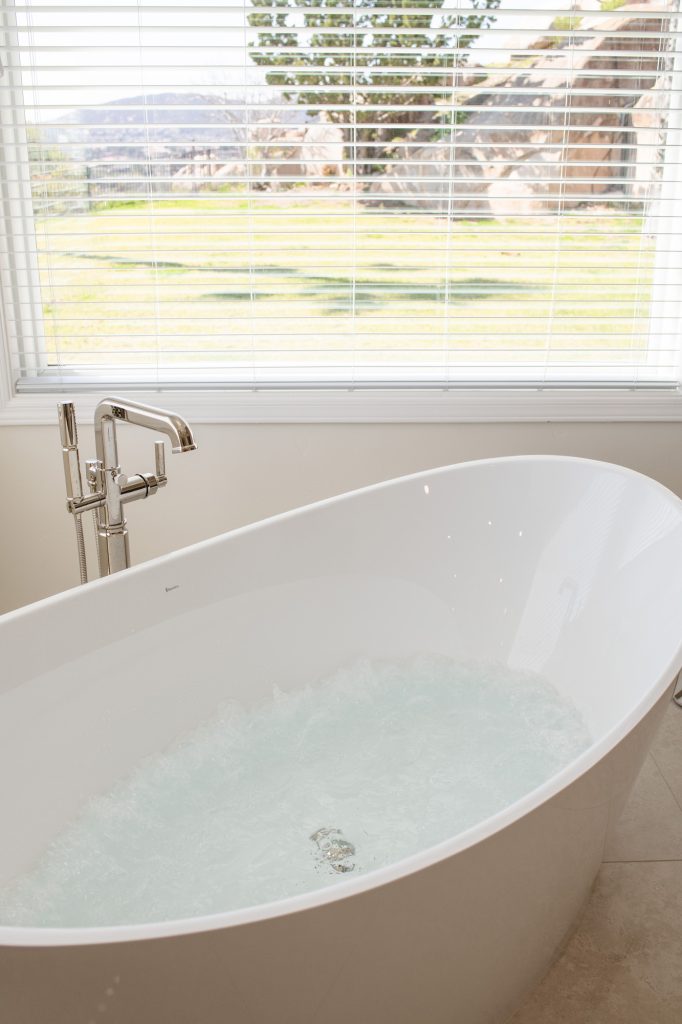 Hydrotherapy bubbles churning in BainUltra tub while hillside scenery is visible through the window.