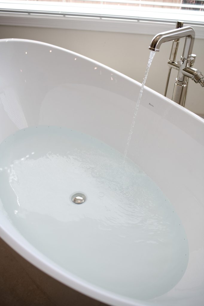 Freestanding tub filling with heated micro-bubble water therapy for a spa-like soak.