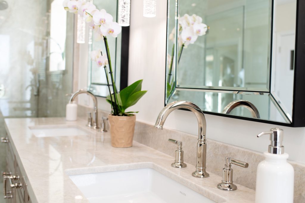 Side perspective of dual-sink vanity featuring orchid planter, crystal pendants and polished-nickel faucets.