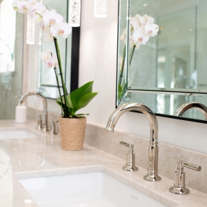 Side perspective of dual-sink vanity featuring orchid planter, crystal pendants and polished-nickel faucets.