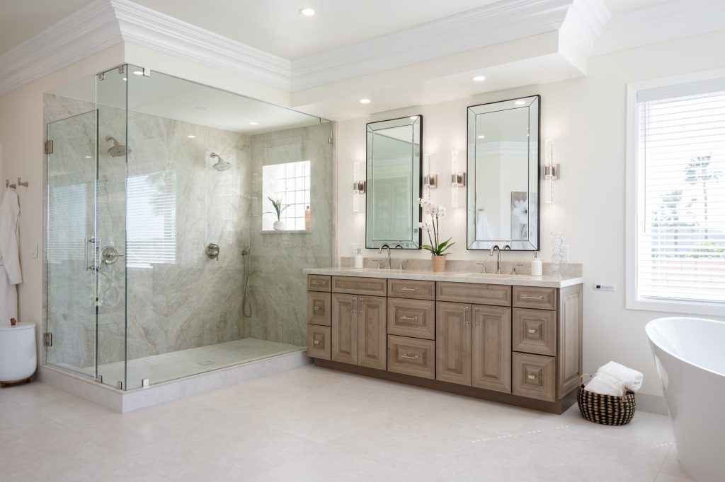 Glass-enclosed Taj Mahal quartzite shower beside maple-almond double vanity in Poway luxury bath remodel