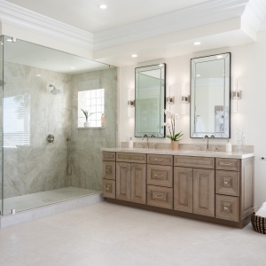 Glass-enclosed Taj Mahal quartzite shower beside maple-almond double vanity in Poway luxury bath remodel