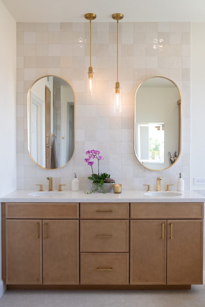 Double-sink maple vanity with brushed-gold faucets and pendant lights.