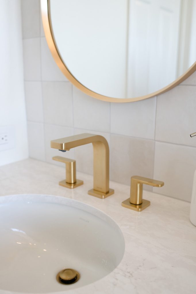 Brushed-gold oval faucet set above polished quartz undermount sink.