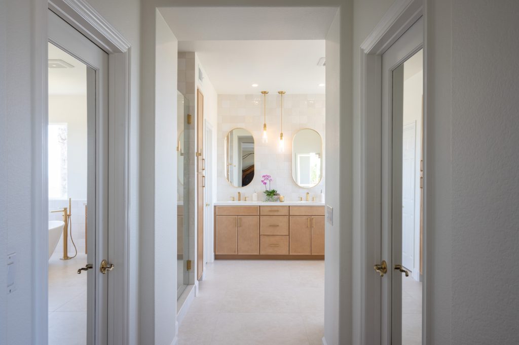 Hallway sightline revealing bright spa bathroom with dual vanity.