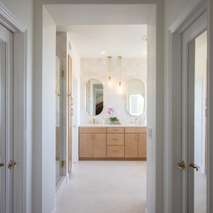 Hallway sightline revealing bright spa bathroom with dual vanity.
