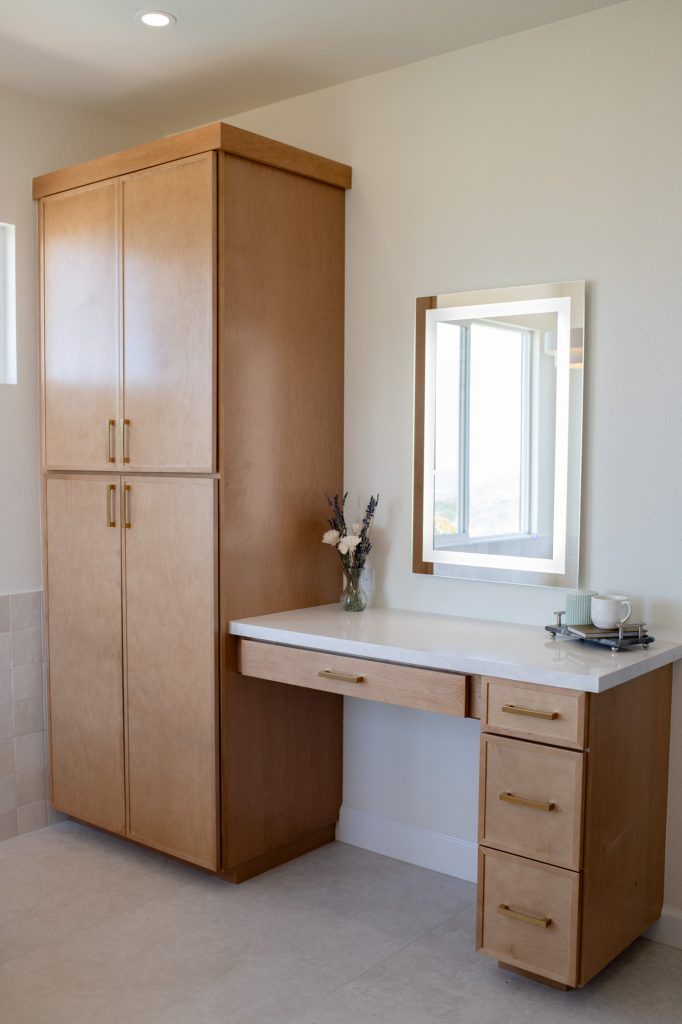 Built-in makeup desk beside full-height linen tower cabinetry.