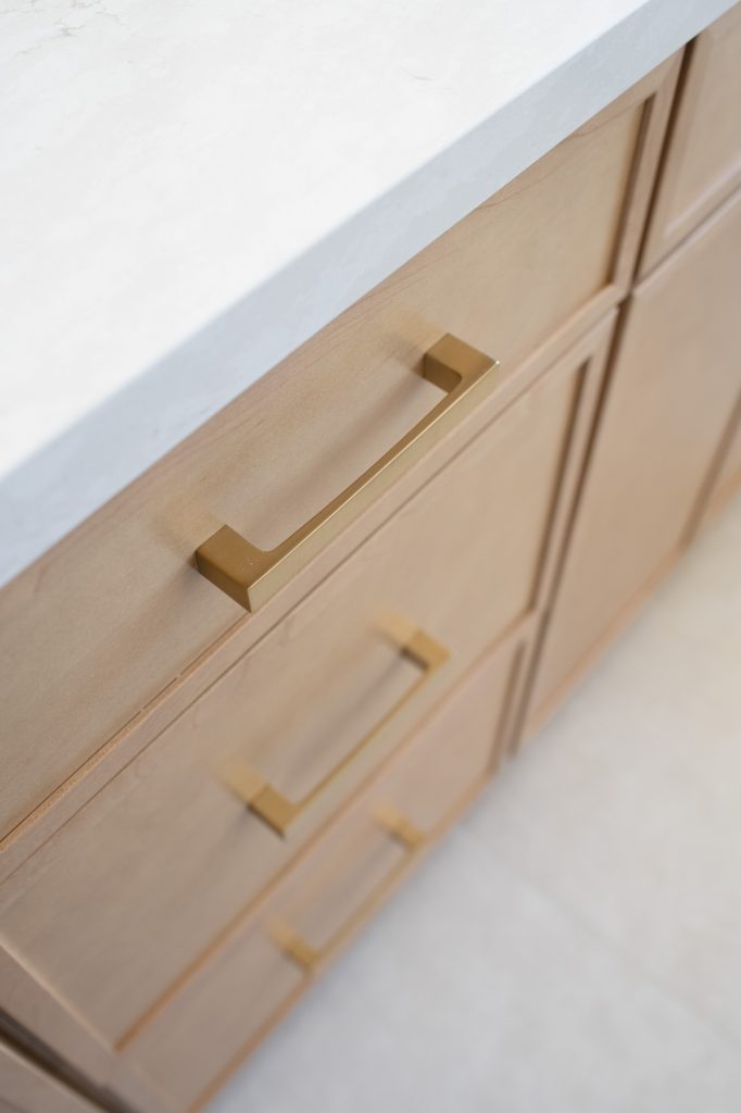 Slim-shaker drawer with brushed-gold pulls and quartz counter edge.