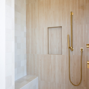 Tiled shower bench and pebble floor meeting vertical slat wall.