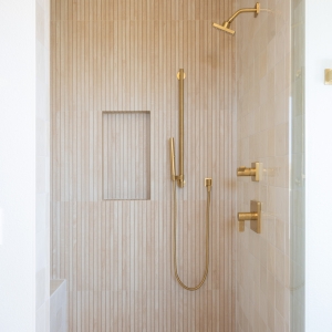 Shower accent wall in vertical Japandi slat tile with gold fixtures.