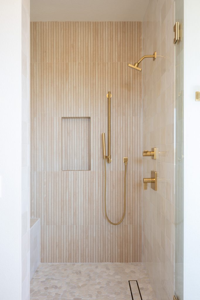 Shower accent wall in vertical Japandi slat tile with gold fixtures.