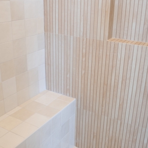 Close-up of mixed square and vertical slat tiles inside shower.