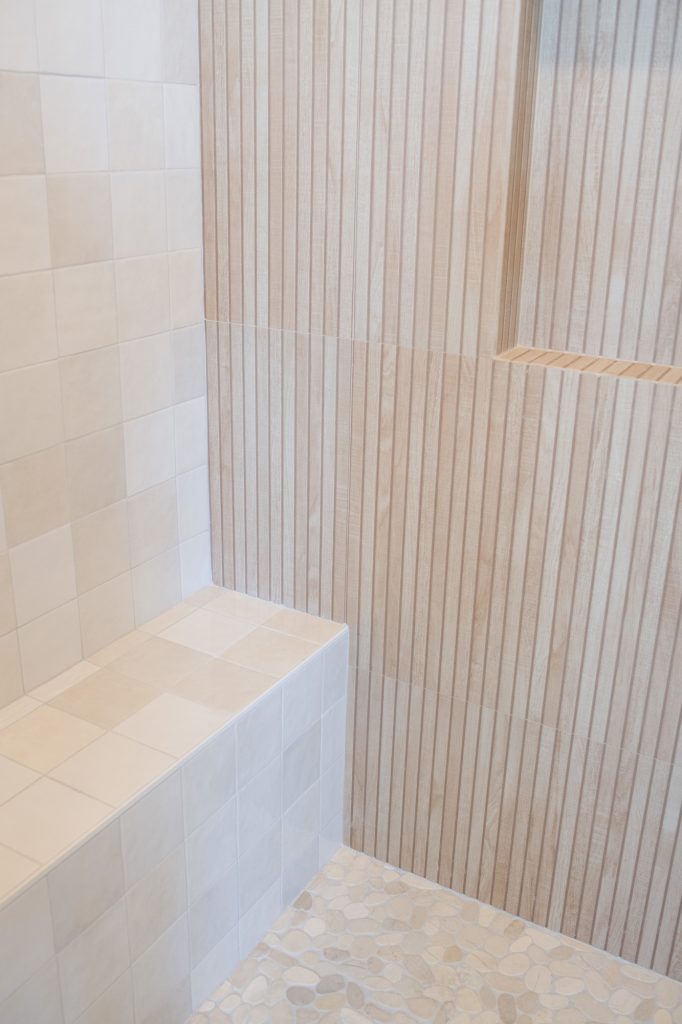 Close-up of mixed square and vertical slat tiles inside shower.