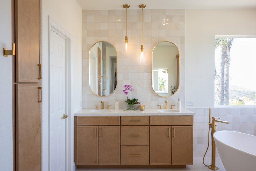 Angle showing vanity and linen tower with coordinated gold hardware.