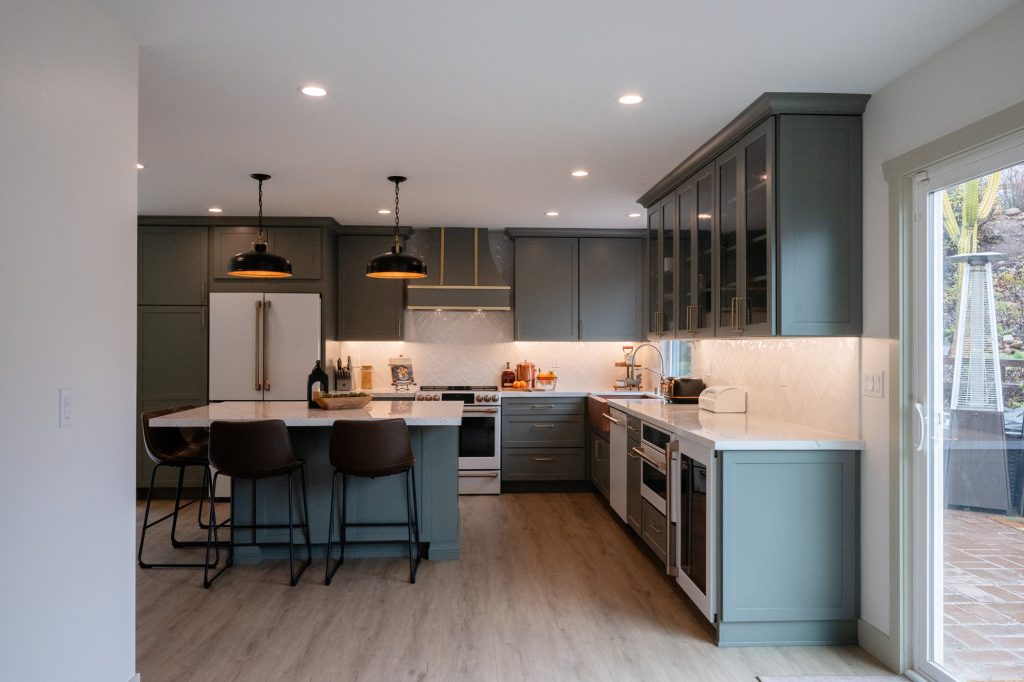 Wide view of sage kitchen and quartz island