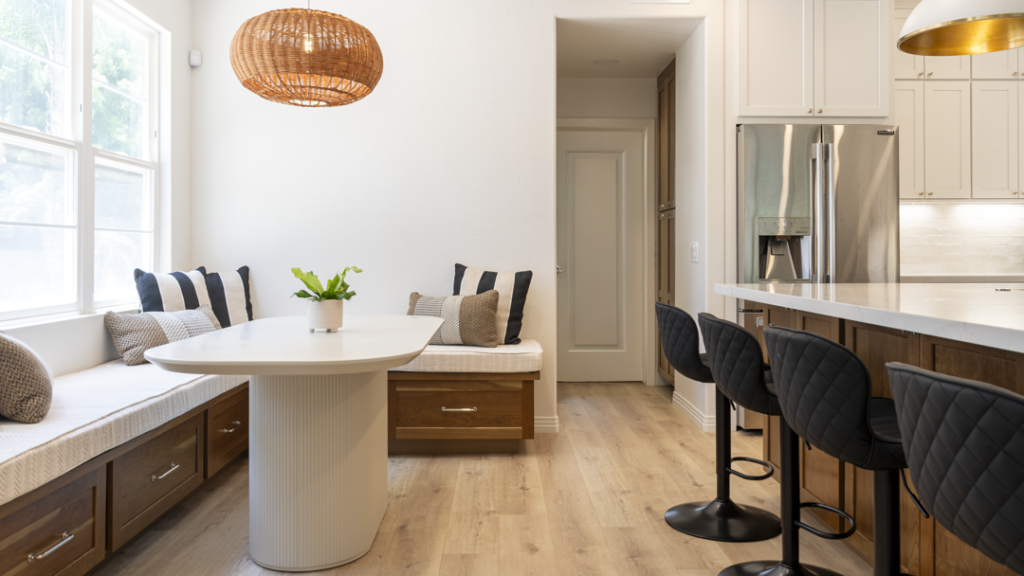 Banquette and island seating area featuring walnut drawer fronts, black swivel stools, and light wood flooring