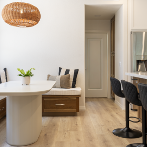 Banquette and island seating area featuring walnut drawer fronts, black swivel stools, and light wood flooring