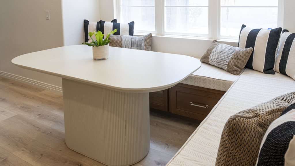 Detail of fluted pedestal table beside chevron-textured banquette cushions and quartz counter edge